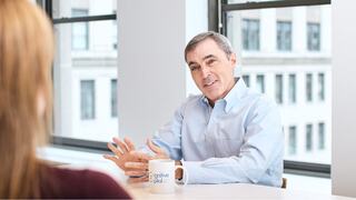 Two professionals engage in a discussion at a conference table.